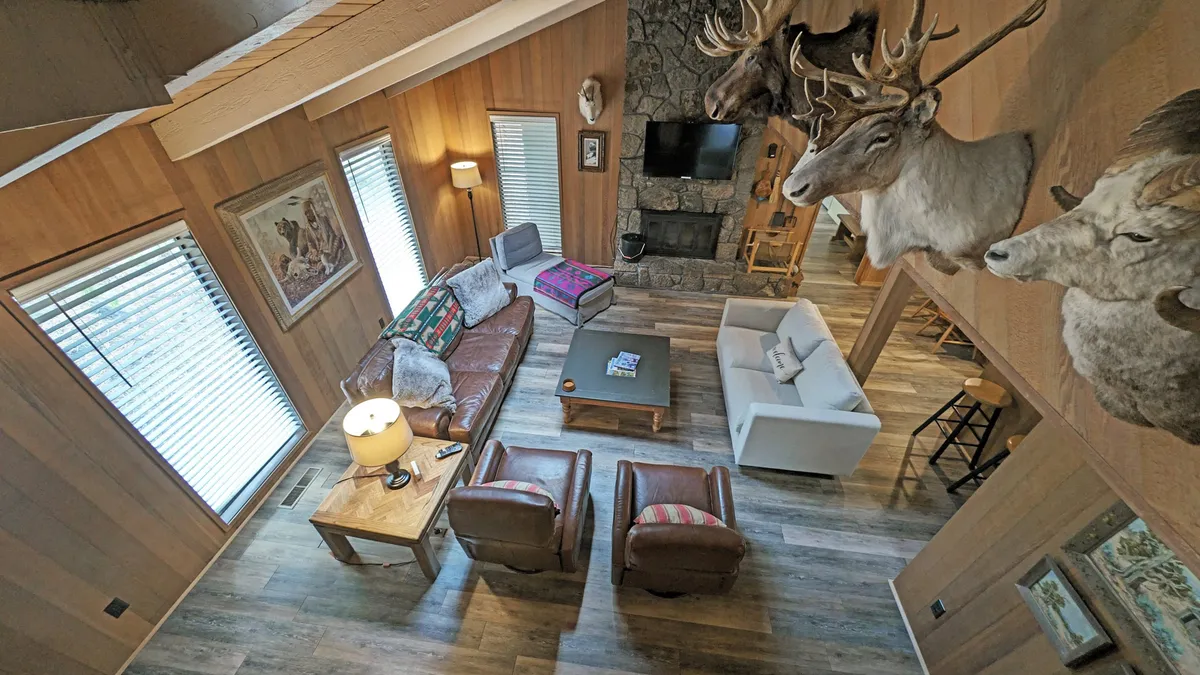 A cozy living room centered around a striking stone fireplace, with leather sofas and rustic decor. The warm lighting and inviting arrangement encourage relaxation and socializing after a day of adventure.