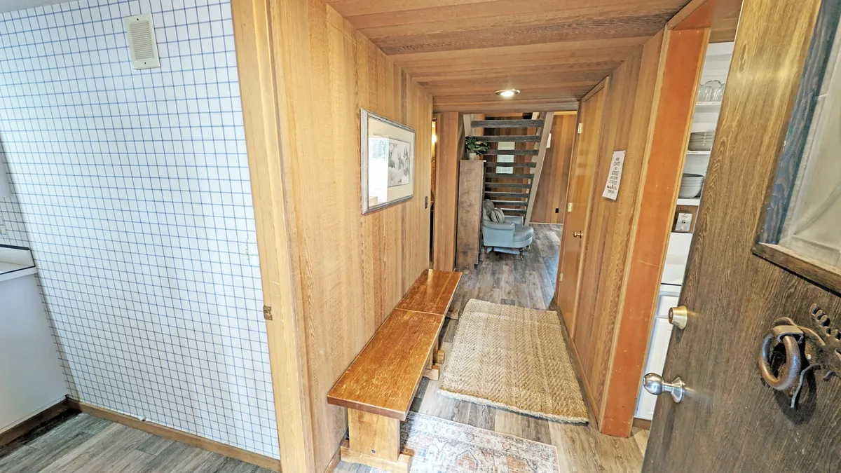 A cozy entryway with a wooden bench, framed artwork, and a staircase leading upstairs. The scene feels welcoming and hints at the transition from outdoor exploration to the inviting spaces inside, including areas dedicated for kids and adults.