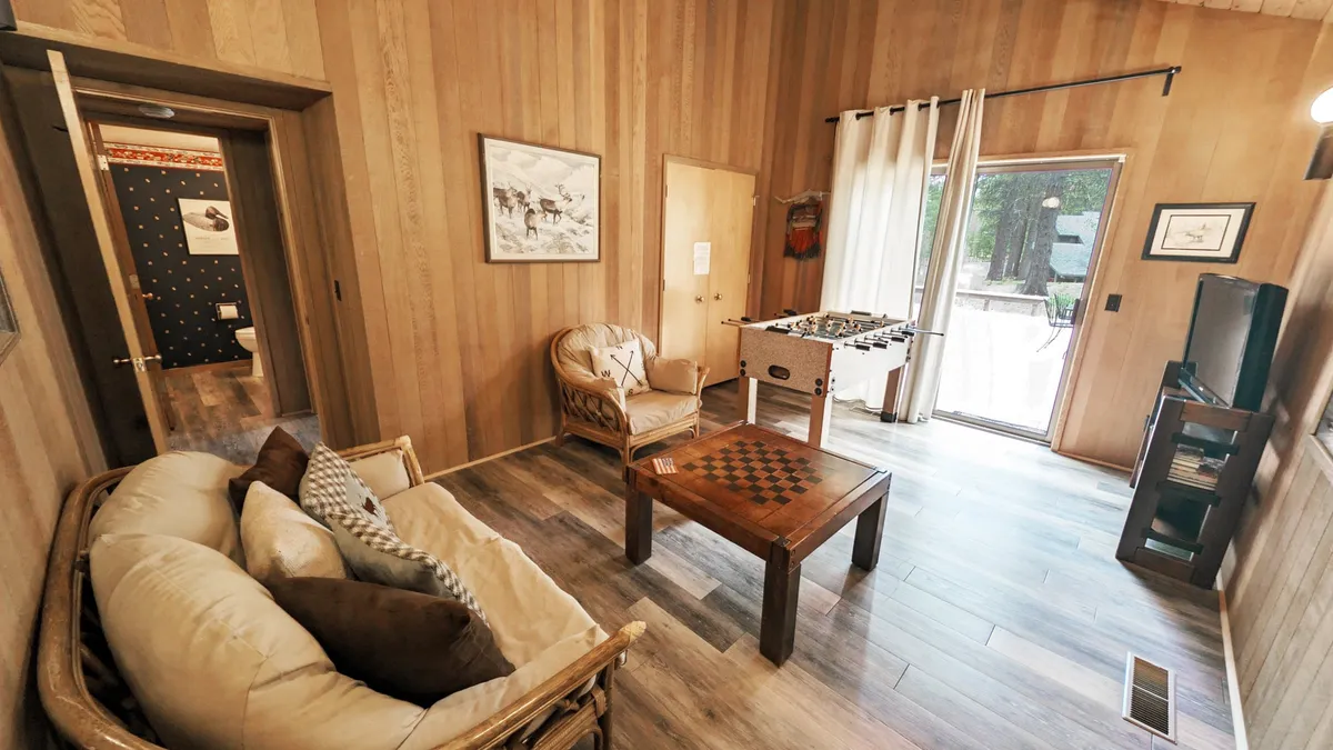 This playful living area features a foosball table, checkers table, comfortable sofa, and wall art, creating an inviting space for post-dinner entertainment and bonding. The mood is relaxed and fun, highlighting the home's array of group-friendly amenities.