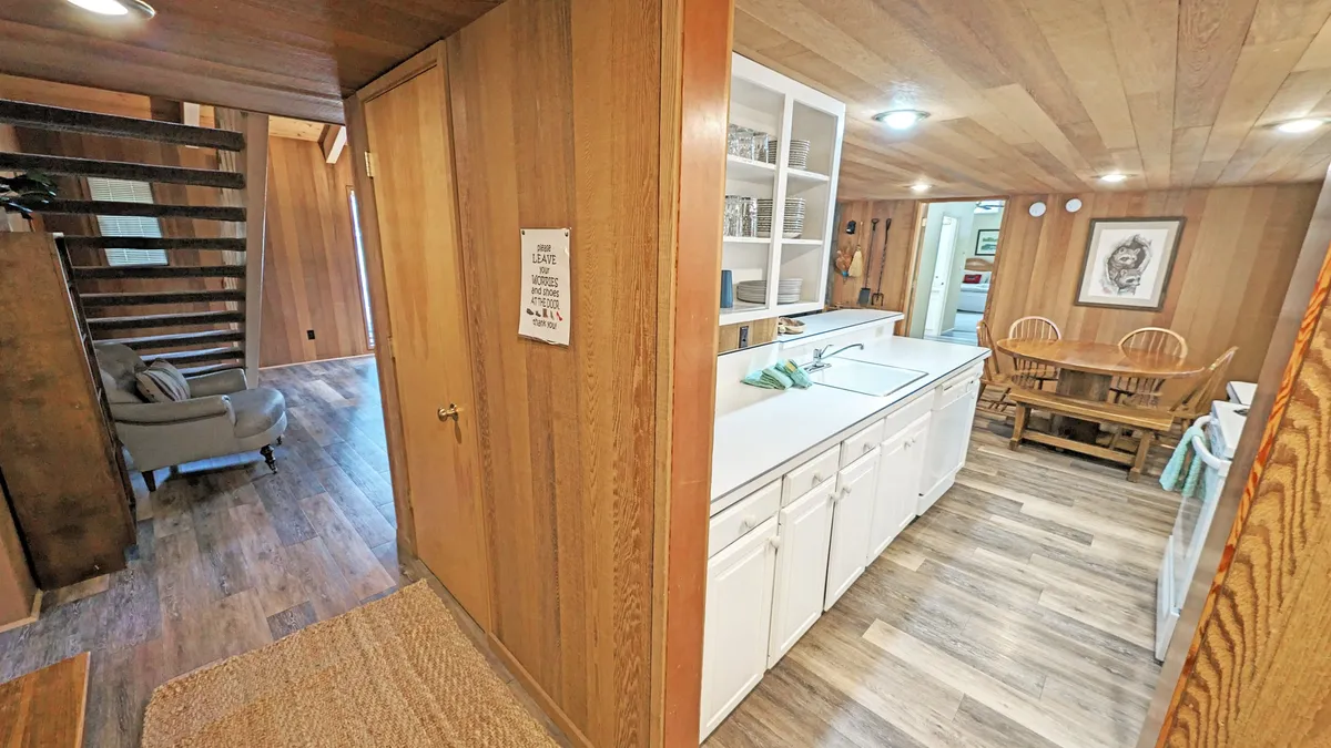 This image showcases the heart of the home, featuring a kitchen counter and adjacent dining table with warm wooden accents and a staircase in the background. The setup exudes a welcoming ambiance, ideal for both cooking and gathering, with visible open sightlines that invite group interaction and shared experiences.